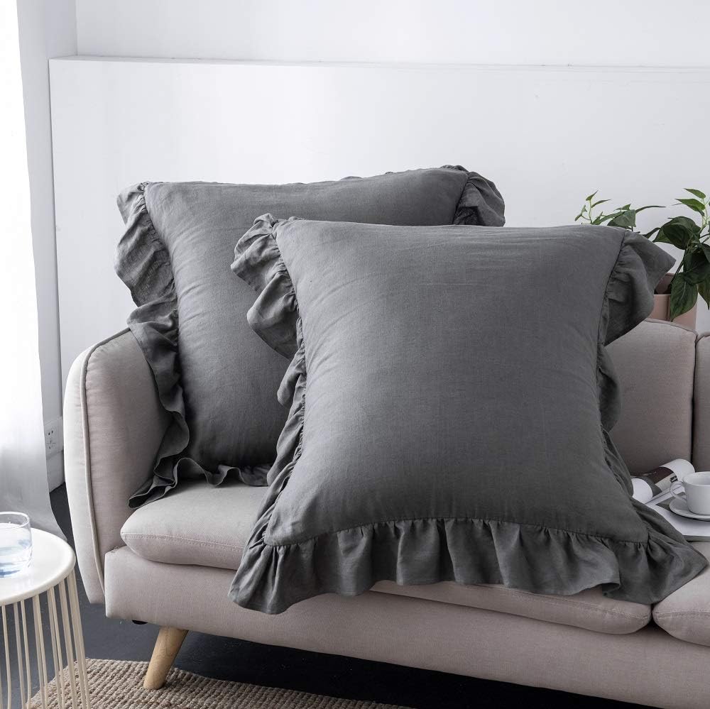 2 Dark gray ruffled linen pillow shams placed on a sofa.