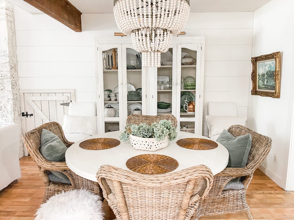 dining room with round table, wood beaded chandelier, and wicker chairs