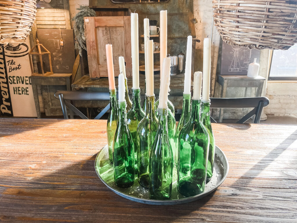 Green glass bottles with white taper candles in them.