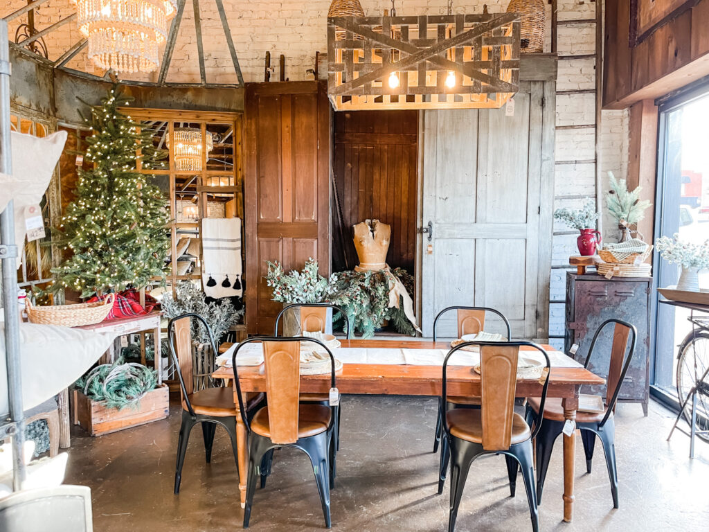 Dining table and metal bistro chairs with Christmas tree and vintage doors