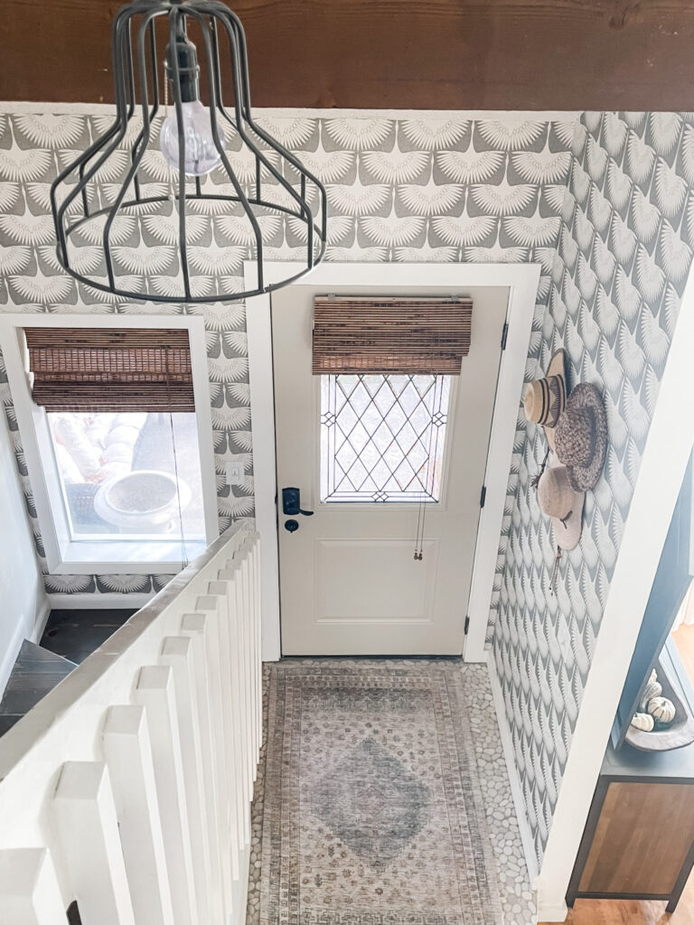 view from upstairs at first floor entryway makeover with gray and white wallpaper.