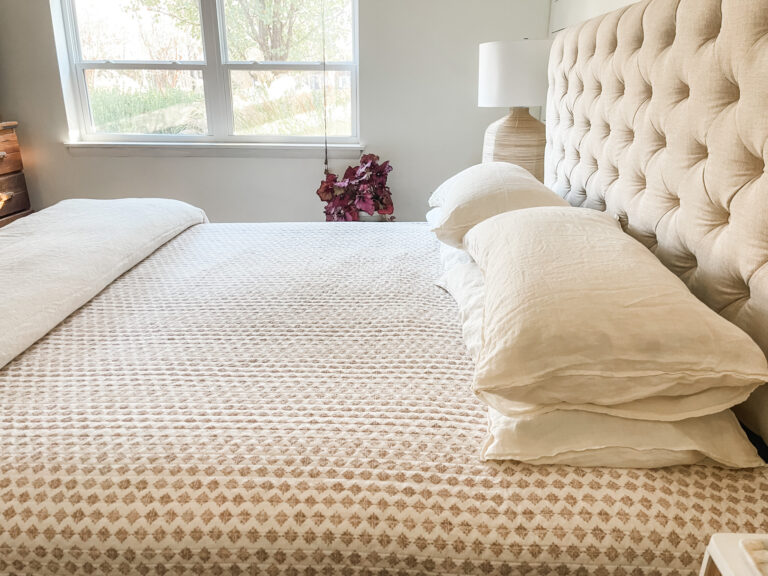 bed with quilt and fluffy pillows, tufted headboard