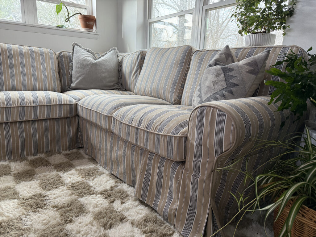 IKEA Uppland sofa sectional with throw pillows and checkered beige and cream rug.