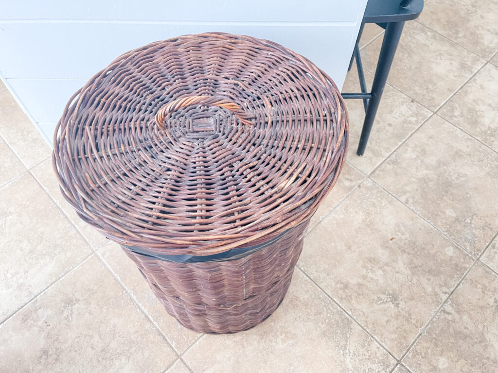 Tall basket with lid used as kitchen trash can.