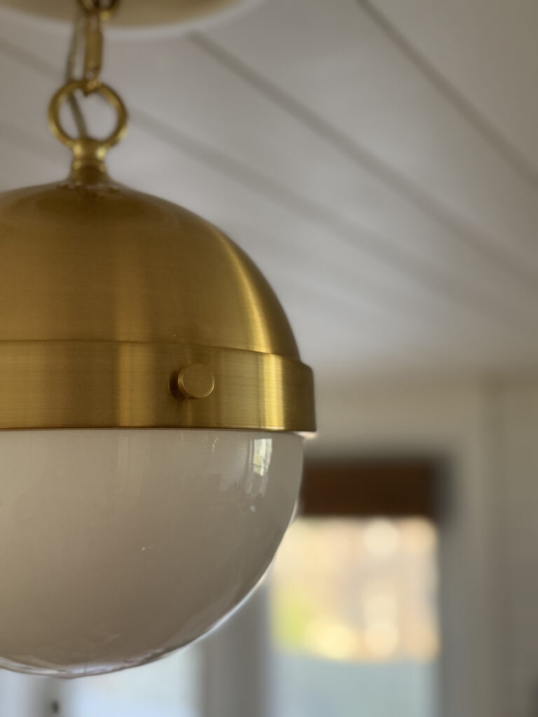 close up of globe pendant light made of brass and milk glass