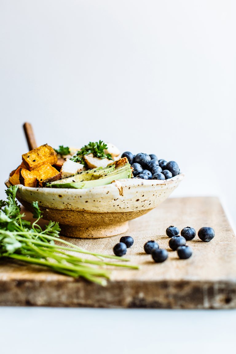 blueberries and vegetables in a wooden bowl on a wooden countertop